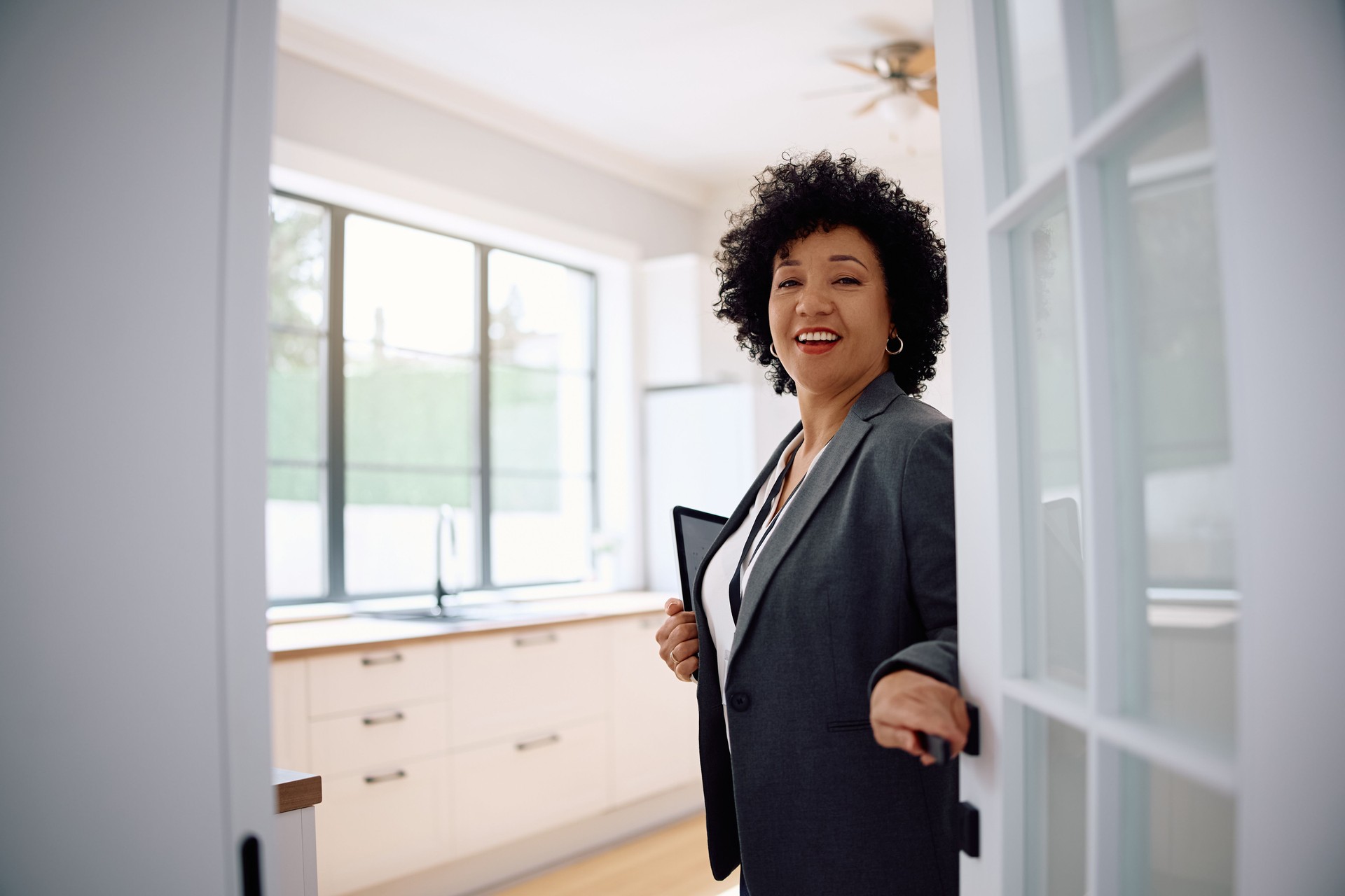 Happy real estate agent welcoming hew clients and looking at camera.